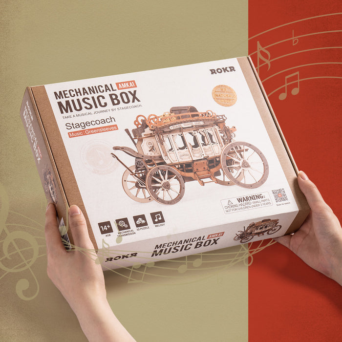 ROKR Stagecoach Music Box retail packaging held in two hands, tan cardboard box with red side panel