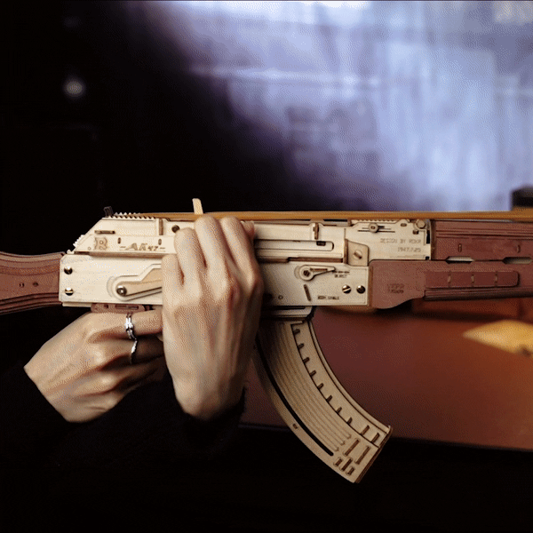 Close-up of hands gripping and assembling the ROKR AK-47 wooden 3D puzzle model showing interior mechanism detail
