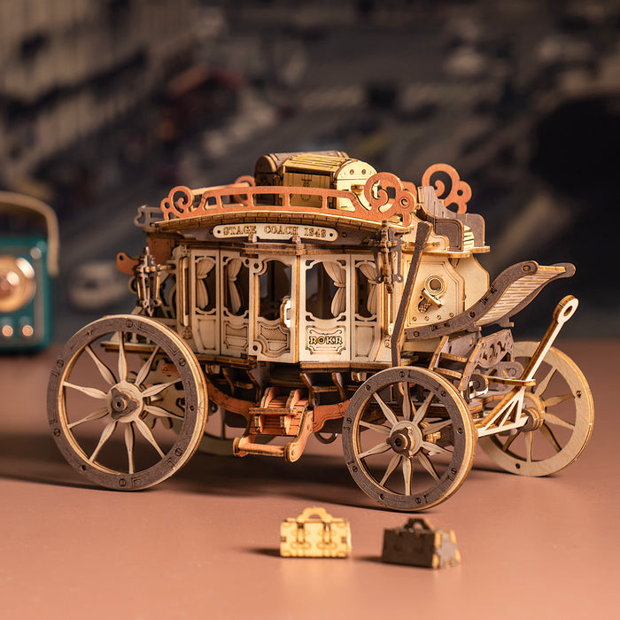 ROKR Stagecoach mechanical music box fully assembled with small wooden luggage accessories on a warm peach surface