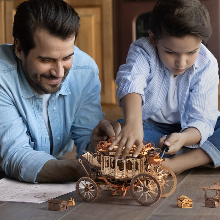 Father and son smiling while assembling the ROKR Stagecoach 3D wooden puzzle together on a living room floor