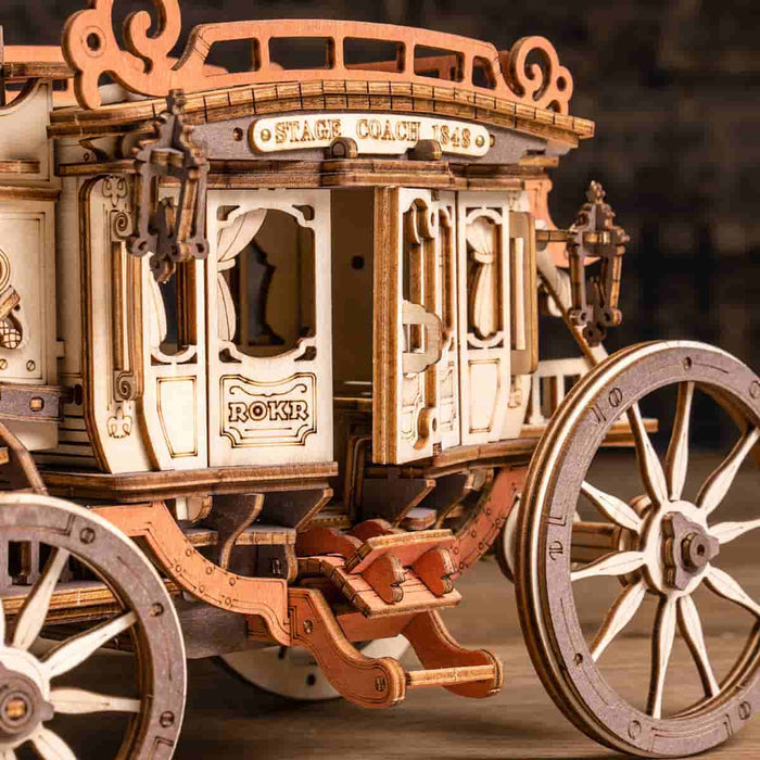 ROKR Stagecoach 3D wooden puzzle close-up showing ornate cream carriage panels, carved trim, and spoked wheels