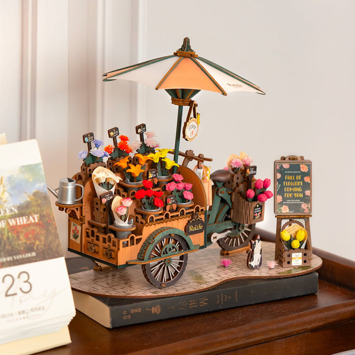 Rolife Blossom Cart miniature on a wooden desk beside a calendar with warm indoor ambient lighting