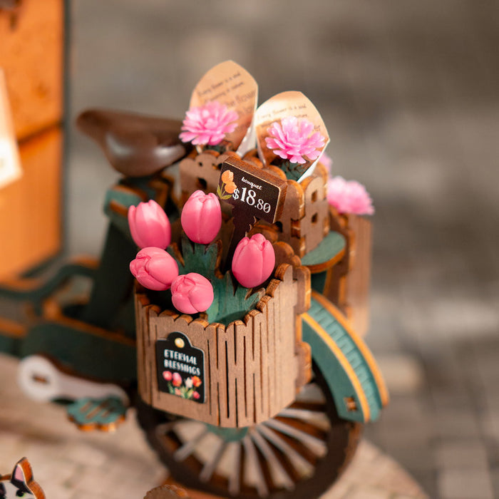 Rolife Blossom Cart bicycle basket close view with pink tulips and a handwritten price tag on warm wood tones